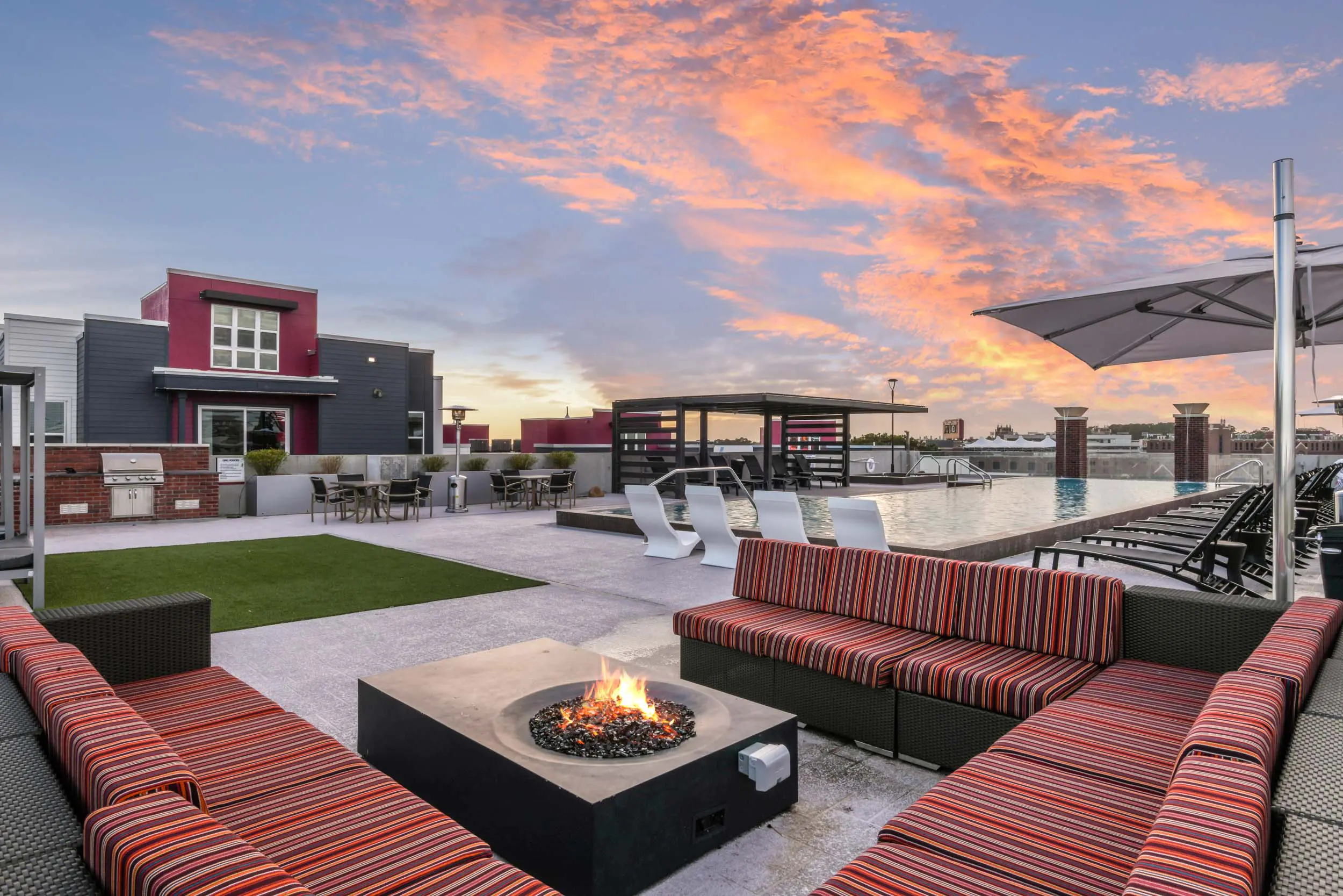 Rooftop pool area with lounge chairs and fire pit.