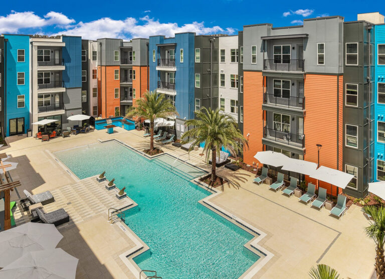 5-story wrap student housing with orange, blue and grey for University of Florida surrounding a courtyard zero-entry pool with blue skies
