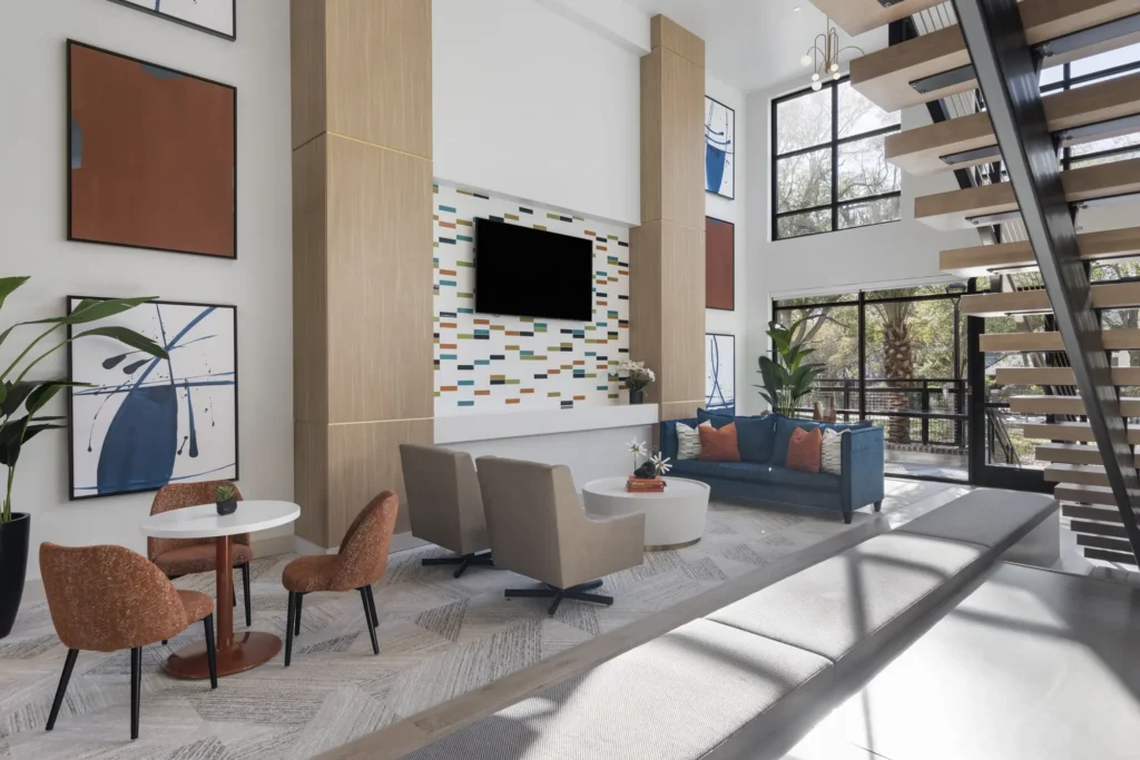 A common space at The Aston at Uptown featuring a conversation area, a bistro table and chairs, and an open staircase.